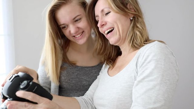 Mum and daughter operating camera, teenager girl showing her mother pictures she take with her DLSR camera