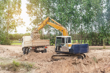 Yellow excavator machine loading soil into a dump truck at construction site