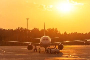 Fototapeta na wymiar Passenger airplane during push back operation, evening airport at sunset