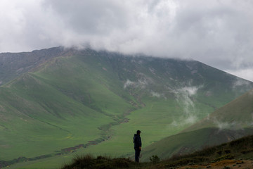 Obraz premium Man standing of the pick and looking at the beautiful mountain. Landscape, mountain in the clouds. Armenia.
