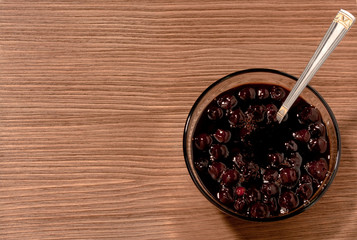 bowl of cherry jam on a brown wooden background