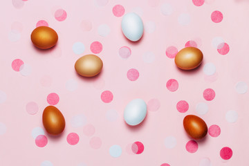 Easter eggs background with confetti and glitter. Festival and bright yellow background. Top view, flat lay.
