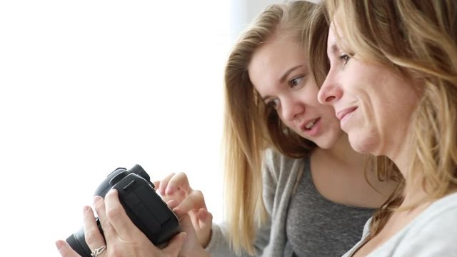 Mum and daughter operating camera, teenager girl showing her mother pictures she take with her DLSR camera