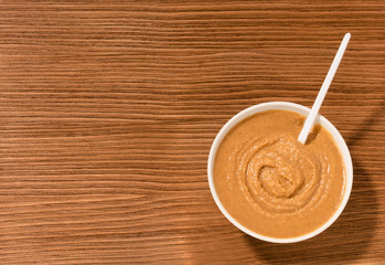 bowl with mustard and spoon on brown wooden background