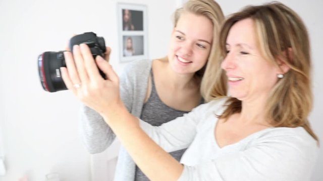 Mum and daughter operating camera, teenager girl showing her mother pictures she take with her DLSR camera