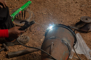 Welder is welding metal piping in construction site