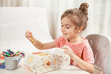 Cute little girl drawing with pencils at home