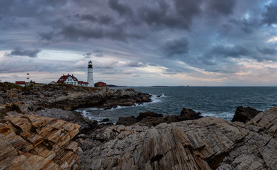 Beautiful panoramic view of Portland Head Lighthouse on the Atlantic Ocean Coast during cloudy sunset. Taken in Fort Williams Park, Portland, Maine, United States.