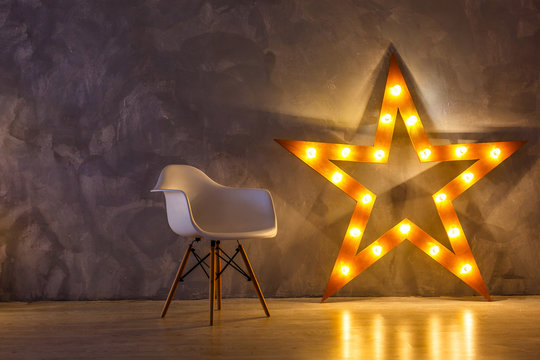 Star lamp on the background of an old wall, on the wooden floor, lights, lights, lights, glare. Exhibition star, light object, interior decor. Abstract dark background, night view, club