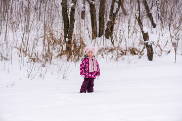 Small girl in pink smiling in winter forest