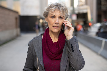 Mature woman in city walking talking on cell phone