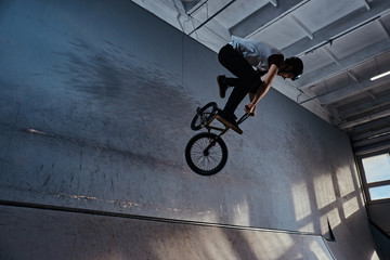 Bmx freestyle. Young BMX making tricks on his bicycle in skatepark indoors - Powered by Adobe