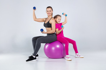 Athletic woman and nice girl doing sport exercises
