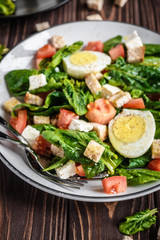Fresh vegetable salad with tomatoes, spinach, bread crumbs, egg and feta. Healthy food. Dietary dinner or lunch menu. Salad plate on the table.