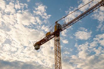 yellow construction crane in cloudy sky