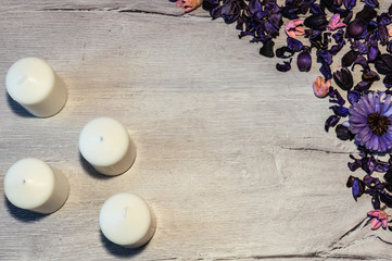 Wooden background decorated with purple flowers and candles. Copy space.