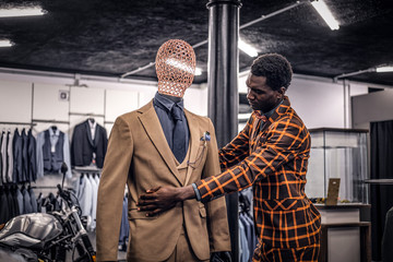 Stylish African-American man dressed in trendy elegant suit, working at classic menswear store.