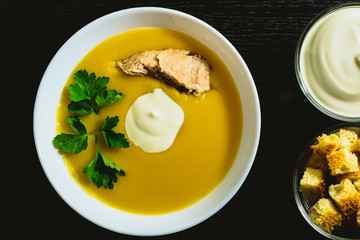 Cream soup in a white plate on a dark background.
