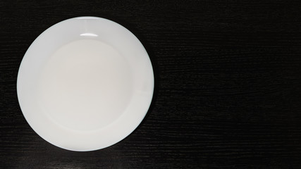 empty white plates on black background, top view
