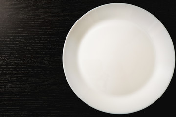 empty white plates on black background, top view