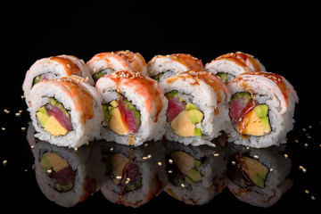 Sushi roll (Maguro) with tuna, shrimp, salmon, smoked eel, avocado, philadelphia cheese on black background. Sushi menu. Japanese food.