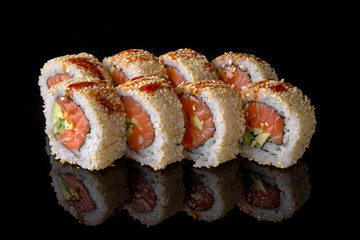 Sushi roll with salmon, egg omelette, avocado, unagi sauce on black background. Sushi menu. Japanese food.