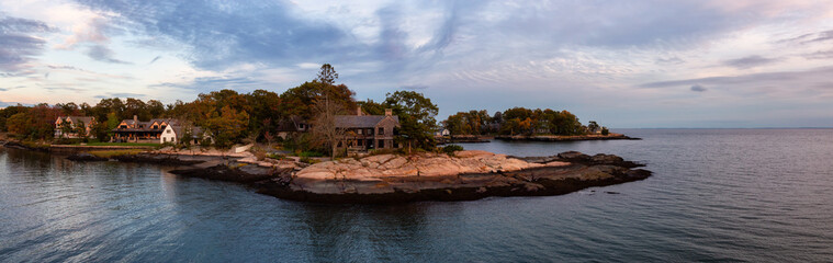 Panoramic seascape view of beautiful homes on a rocky Atlantic Coast during a vibrant sunset. Taken in New Haven, Connecticut, United States. - obrazy, fototapety, plakaty
