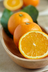 Oranges in a wooden bowl with leaves