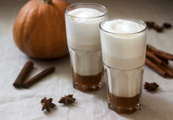 Homemade pumpkin latte in tall glasses and pumpkin on a linen tablecloth. Rustic style.