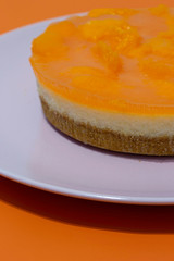 Mandarin orange cheesecake on a pink plate on an orange background