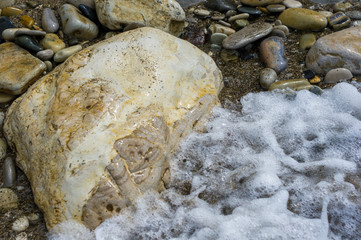pebble stones on the sea beach, the rolling waves of the sea with foam