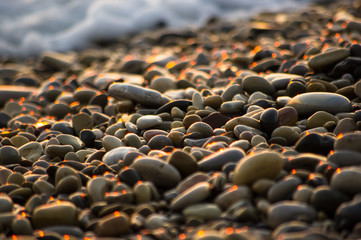Obraz premium pebble stones on the sea beach, the rolling waves of the sea with foam