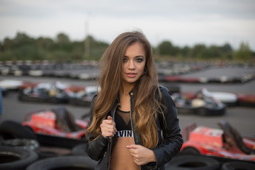 Fototapeta na wymiar Gorgeous beauty model posing outdoors in street racing with tires and cars on background. Speed, sport, beauty concept