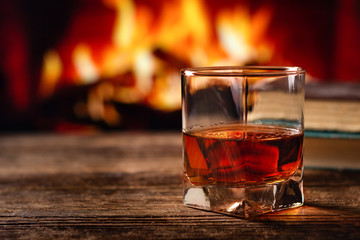 Glass of cognac or whiskey. Blur burning fireplace background.