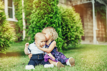 Summer happy time. Two cheerful infant babies outdoors smiling and playing together in green sunny park. Childhood, happiness, infant baby concept