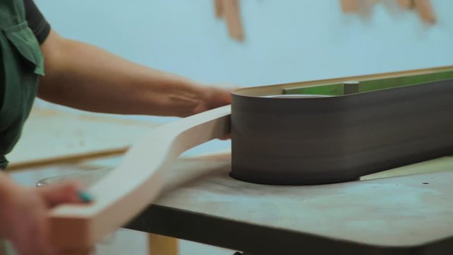 a worker polishes the wooden piece on the belt sander the machine. close up. sanded stool parts .