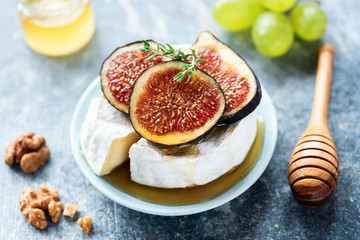 Brie cheese or camembert on cheese platter with crackers, grapes, olive oil. Closeup view, selective focus