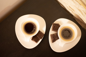 Dwie białe filiżanki espresso na brązowym stoliku - obrazy, fototapety, plakaty