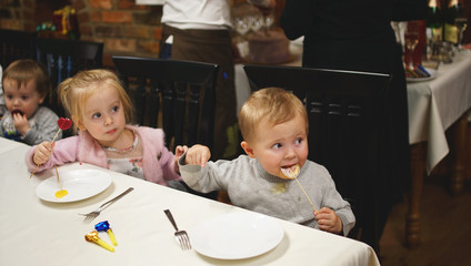 Cute little girl and boy sitting at the table on the birhday