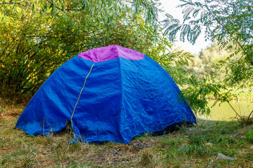 Blue camping tent in forest near a river