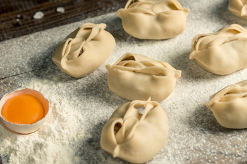 Uzbek national food manta, like dumplings, on a wooden board, lie in flour with an egg