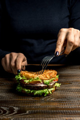 Healthy lifestyle, proper nutrition. Female hands cut a useful rice burger with vegetables, herbs and cutlet on a wooden board
