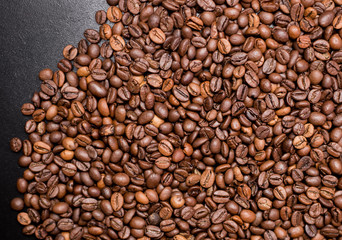 Coffee in beans on dark background. Abstract Food background texture, roasted coffee beans, top view