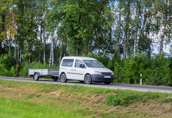 Car with a Trailer moves on a country road