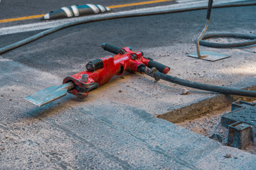 Red jackhammer at construction site.