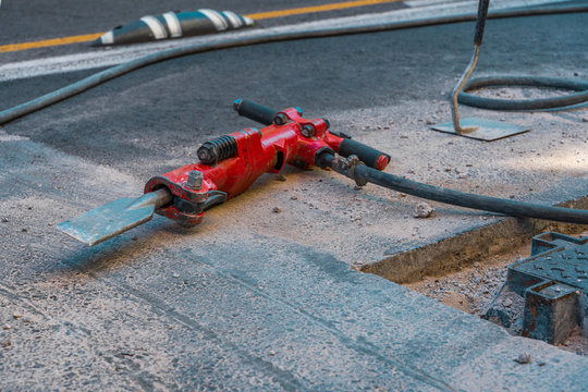 Red jackhammer at construction site.