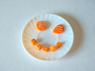 Smile face from vegetables on a white plate on a white background