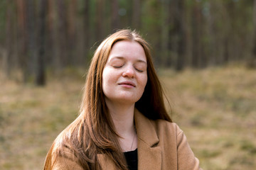 Smilimg dreaming woman with closed eyes in the forest. Positive and growth mindset