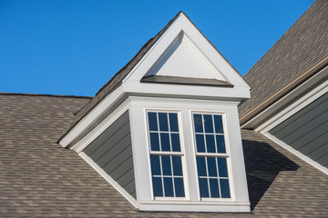 White dormer sash window on a gable roof with vinyl siding on a luxury estate house in the East Coast of the USA for upper middle class families