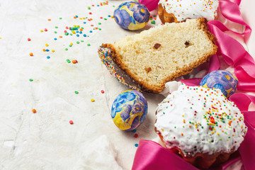 Easter cake and one piece, pink ribbon, colorful sweets on a light background. The concept of Orthodox Easter